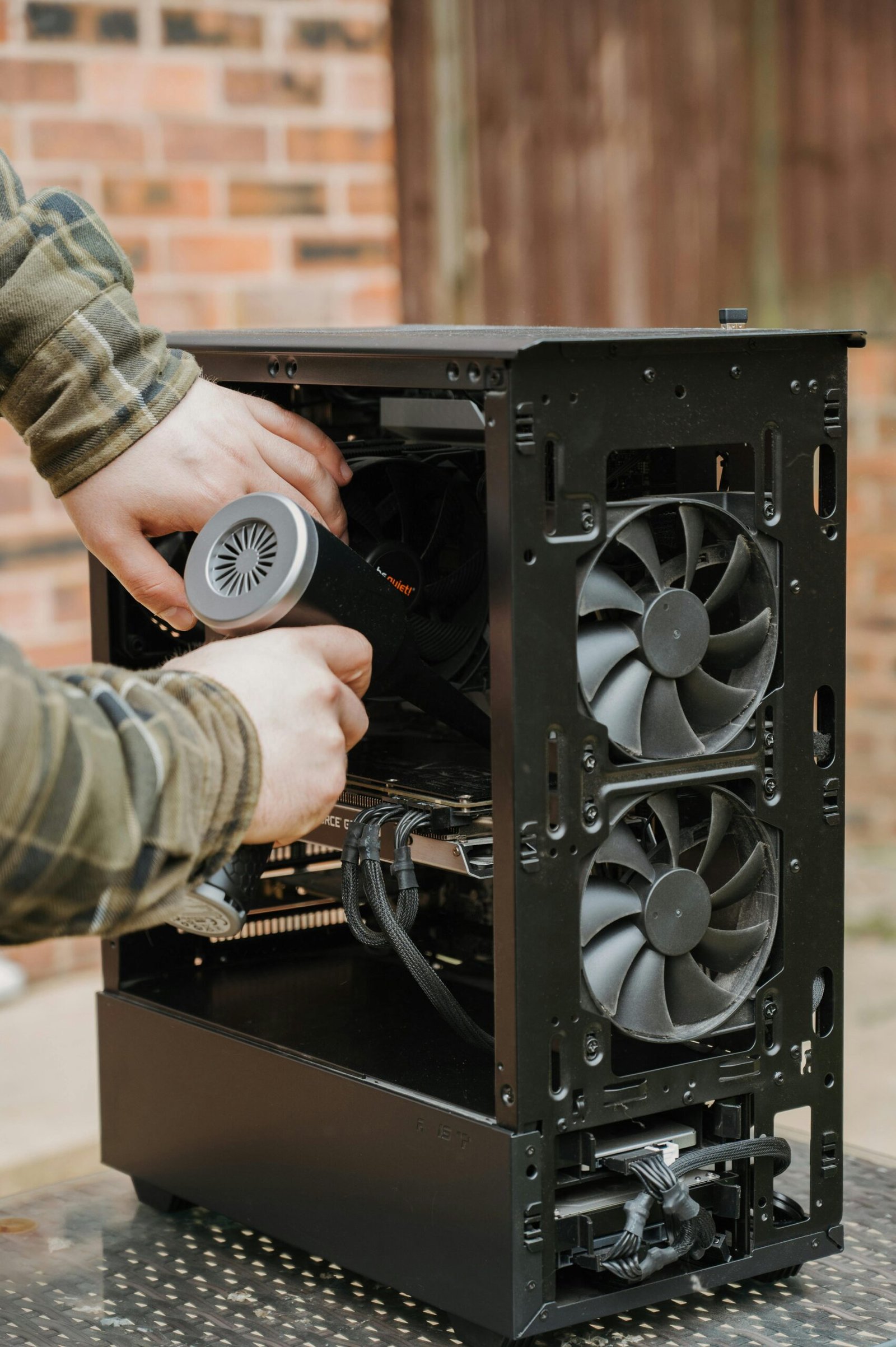 Close-up of hands cleaning the interior of a PC case with a duster, focusing on computer care and maintenance.